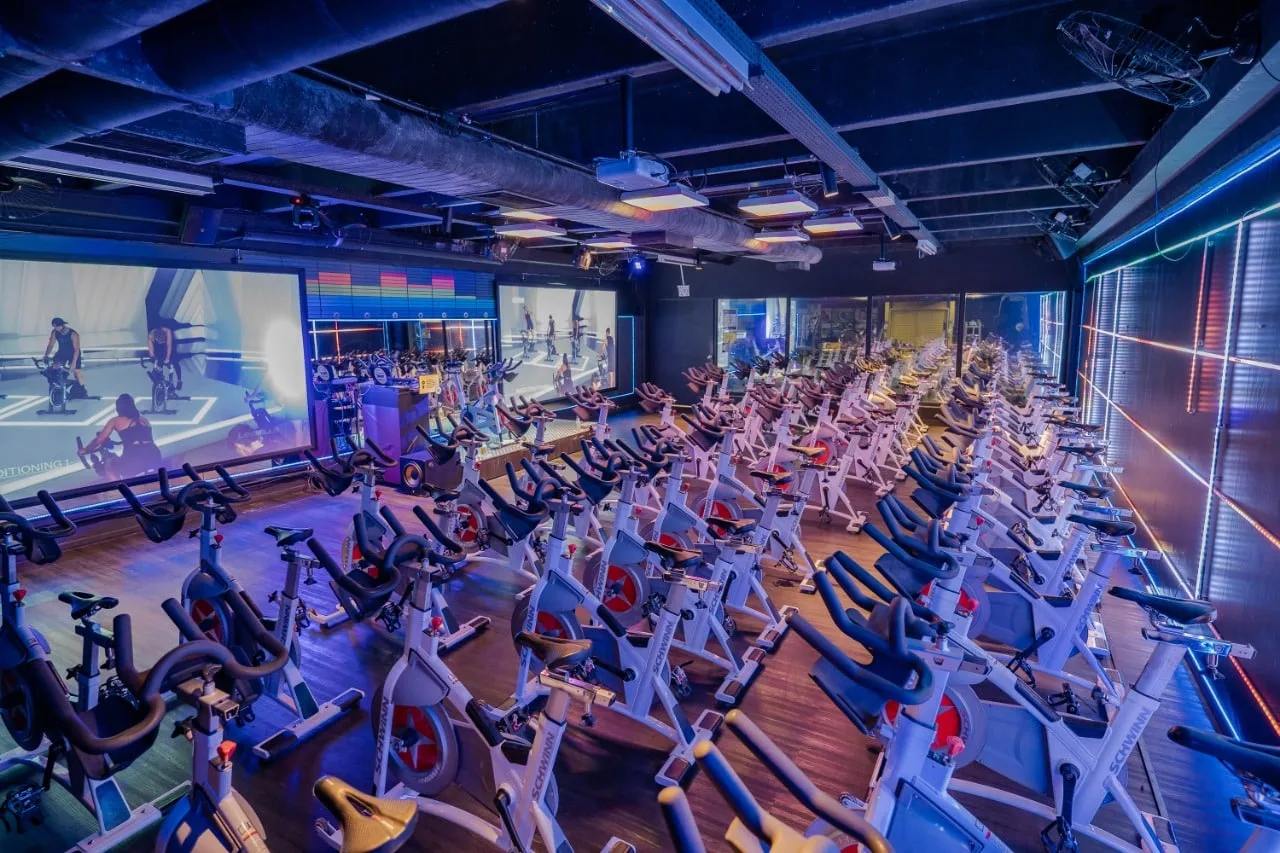 Sala de ciclismo indoor com bikes e iluminação azul